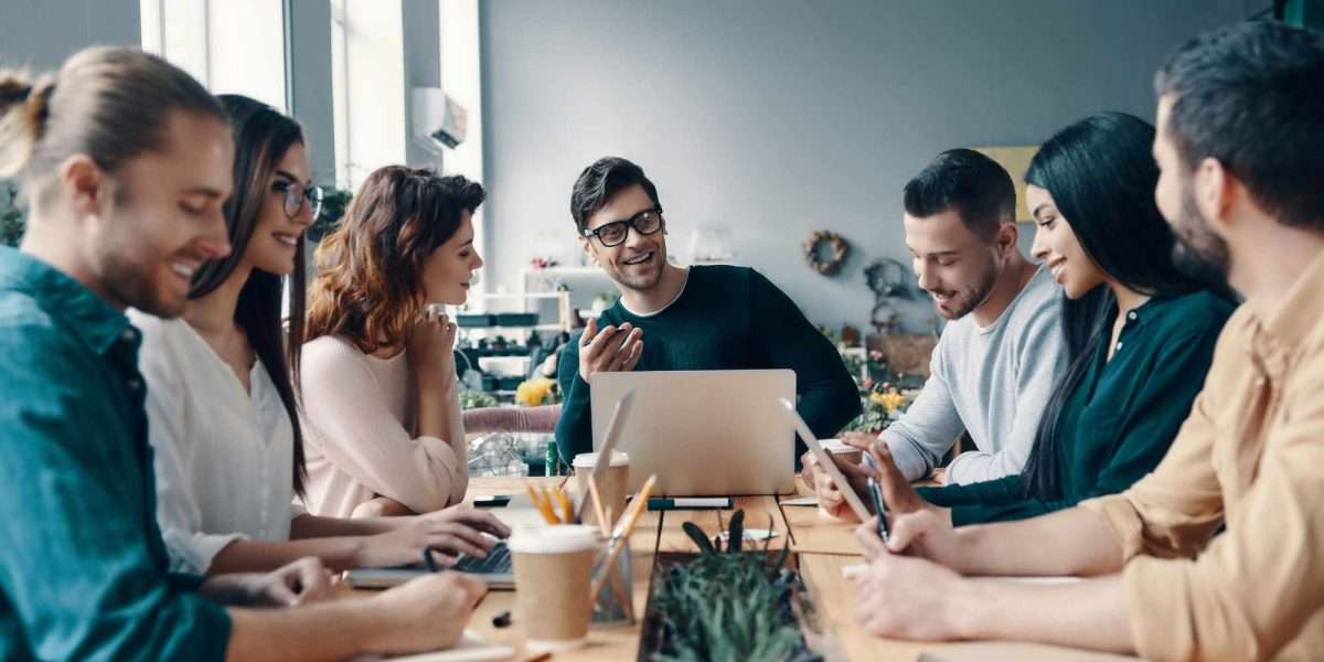 A group of young digital professionals are sitting around a conference table discussing ideas