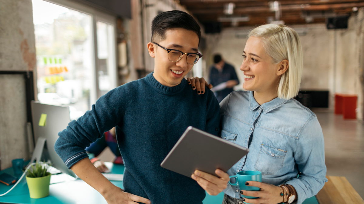 Two young creative professionals discuss something while looking at an iPad