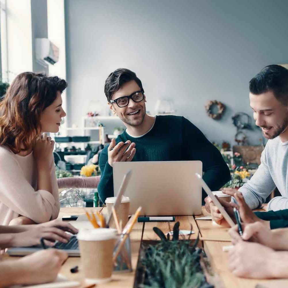 A group of young digital professionals are sitting around a conference table discussing ideas