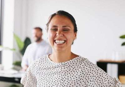 Hire marketing apprentice Woman in an office smiling broadly at camera in a casual pose wearing a white t-shirt with black spots